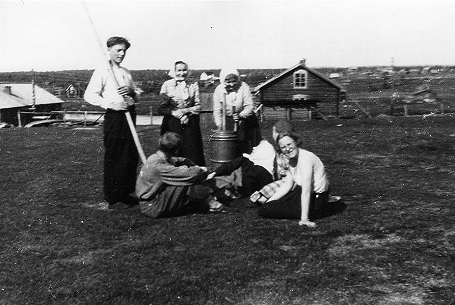 Lainio 02 E.jpg -  Fredrika Johansson "Erkkin Rika" kärnar smör på Ollas gård. Till vänster om henne står Hulda Olla och sittande ser vi Isak och Huldas dotter Alma.